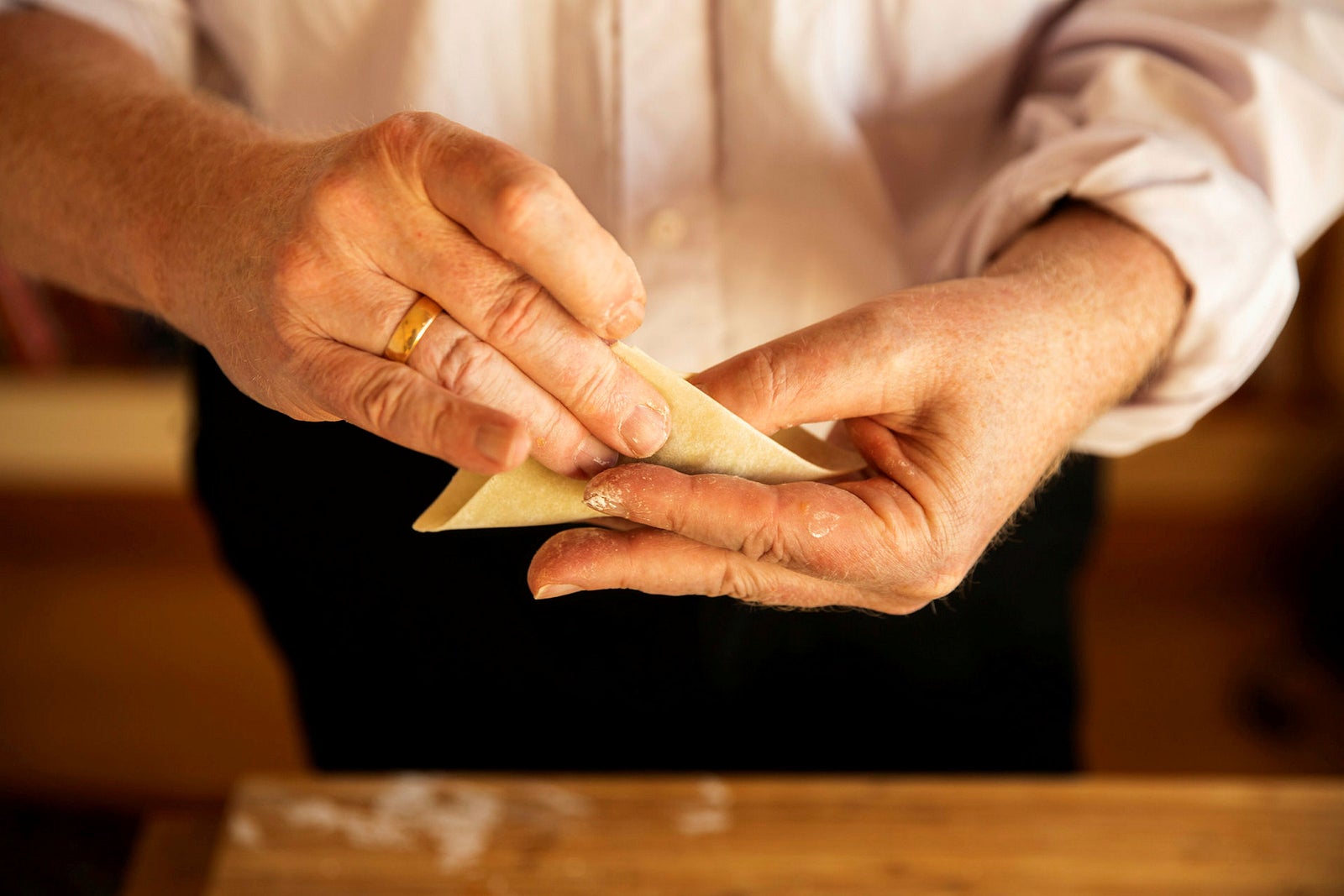 Pakk inn. Hvis du er høyrehendt, legger du dumplingen i venstre, stryker på vann med høyre pekefinger, bretter med høyre hånds fingre og bruker venstre tommel for å dytte fyllet på plass.