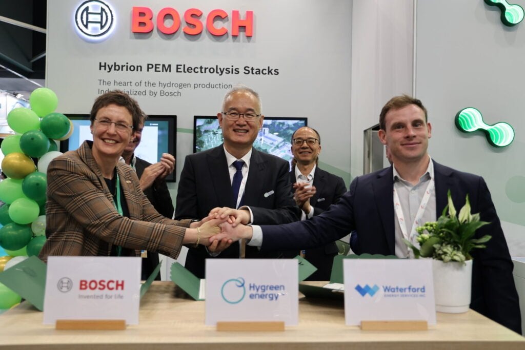 Hygreen CCO Alan Tan, centre, shakes hands with unidentified Bosch and WESI executives at the Bosch exhibition stand at the World Hydrogen Summit in Rotterdam.