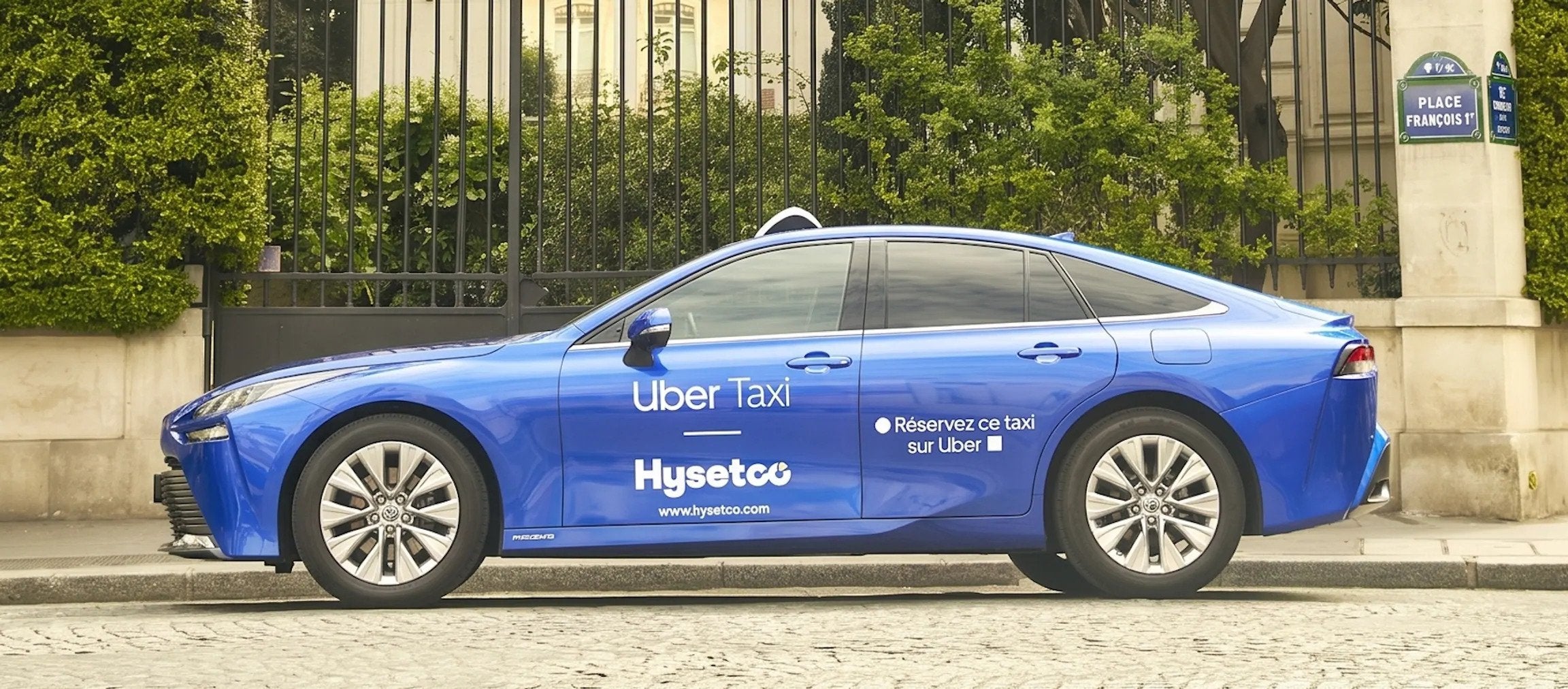 A Toyota Mirai branded with both the Uber Taxi and HysetCo logos.